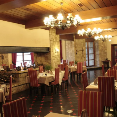 Ein elegantes Restaurant mit rustikalem Steininterieur, das mit warmem Licht und stilvollen roten Stühlen dekoriert ist.
