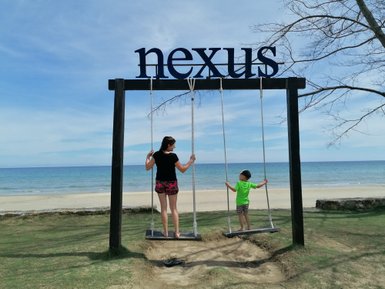 Mutter schaukelt gemeinsam mit ihrem Kind am Strand des Nexus Resorts – Malaysia & Borneo Reise mit Kindern