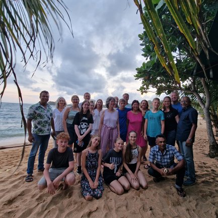 Reisegruppe posiert gemeinsam für ein Foto am Sandstrand unter Palmen – Sri Lanka Familienreise