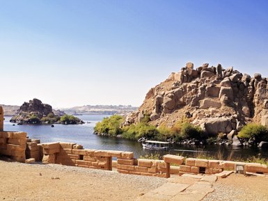 Die stillen Wellen des Nils reflektieren die umliegenden Felder und die majestätischen Felsen in Ägypten.