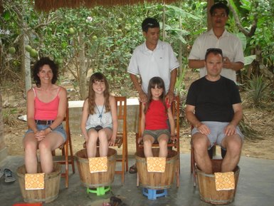 Eine Gruppe von fünf Personen sitzt in Holzfässern, während sie in einer grünen, üppigen Umgebung entspannen.