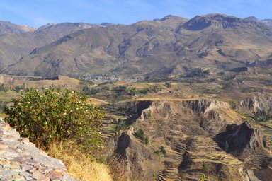 Eine atemberaubende Aussicht auf die zerklüfteten Berge und das grüne Tal des Colca-Canyons unter klarem Himmel.