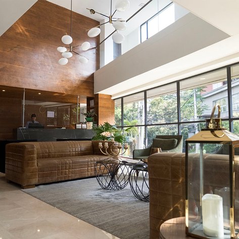 Der Empfangsbereich eines modernen Cafés mit eleganten Möbeln und großen Fenstern, die viel Tageslicht hereinlassen.