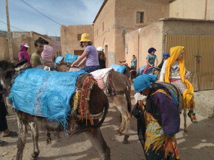 Eine Gruppe von Kindern reitet auf Eseln, während sie in einer engen Gasse mit traditionellen Gebäuden stehen.