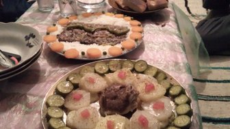 Ein reichhaltiges marokkanisches Essen mit verschiedenen Gerichten auf einem Tisch, umgeben von Gläsern und Wasserkrug.
