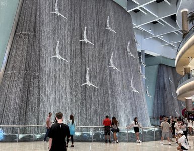 Eine beeindruckende Wasserfallinstallation mit tanzenden Figuren zieht die Aufmerksamkeit der Besucher in einem modernen Einkaufszentrum an.