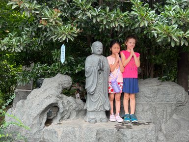 Kinder posieren neben traditionellen Statuen vor der Großen Wildganspagode in Xi’an – China Reise mit Kindern