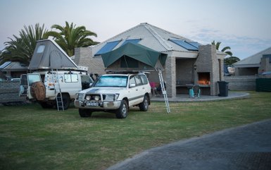Campingbereich im Alte Brücke Resort mit Geländewagen, Dachzelten und Grillstelle vor den Bungalows - Namibia Familienreise