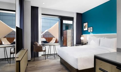 Ein modernes Schlafzimmer mit einem großen Bett, einem Schreibtisch und einem Stuhl, das viel Tageslicht erhält.