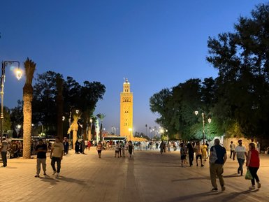 Die Djemaa el-Fnaa in Marrakesch ist bei Nacht lebhaft, mit bunten Lichtern und vielen Menschen, die die Atmosphäre genießen.