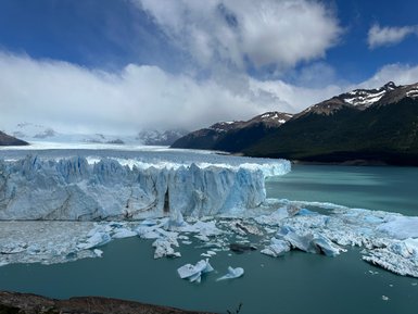 Der Perito Moreno Gletscher erstreckt sich majestätisch über das türkisfarbene Wasser, umgeben von schneebedeckten Bergen.