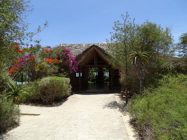 Ein einladender Eingang zu einem tropischen Hotel, umgeben von bunten Blumen und üppigem Grün.