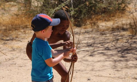 Ein Kind versucht einen Bogen zu spannen - Namibia Urlaub mit Kindern