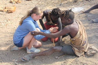 Besucherin übt das Feuer machen mit dem Hadzabe-Stamm – Tansania Familienreise