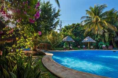 Ein einladender Pool umgeben von üppigem Grün und bunten Blumen, ideal für entspannende Momente in der Natur.