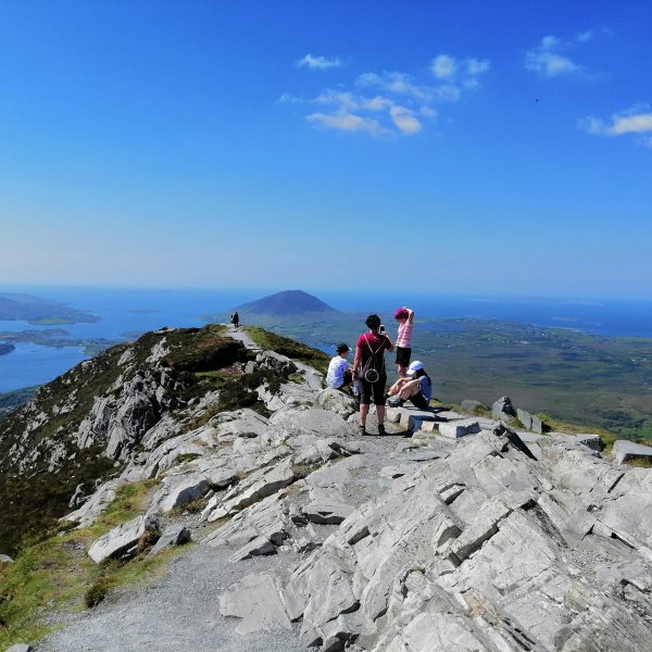 Eine Gruppe von Wanderern genießt die atemberaubende Aussicht auf die Küste und das grüne Land von Connemara.