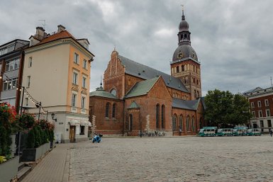 Die beeindruckende Backsteinkirche mit ihrem hohen Turm steht im Mittelpunkt eines ruhigen Platzes, umgeben von historischen Gebäuden.