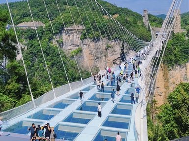 Eine schwebende Glasbrücke verbindet zwei Felsvorsprünge, während zahlreiche Besucher die Aussicht genießen.