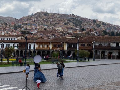 Eine Frau in einem blauen Kleid posiert für ein Fotoshooting auf einem gepflasterten Platz in Cusco, Peru.