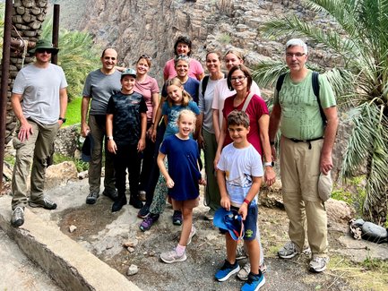 Gruppe fotografiert sich im Wadi Shab mit Bergen im Hintergrund – Oman mit Kindern