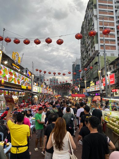 Die belebte Jalan Alor in Kuala Lumpur erstrahlt am Abend mit Streetfood-Ständen – Malaysia & Borneo Familienreise