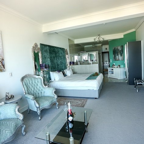 Ein elegantes Hotelzimmer mit einem großen Bett, stilvollen Möbeln und einem modernen Badezimmer im Hintergrund.