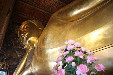 Großer liegender Buddha im Wat Pho Tempel umgeben von Blumen – Thailand Familienreise