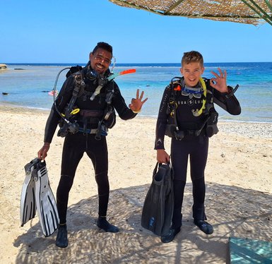 Kind und Guide mit Tauchequipment am Roten Meer - Familienreise nach Ägpyten