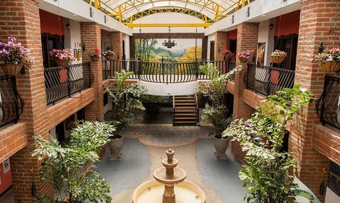 Ein einladender Innenhof mit einer zentralen Brunnenanlage, umgeben von üppigen Pflanzen und bunten Blumenarrangements.