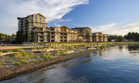 Ein modernes Resort am Wasser, umgeben von üppigem Grün und einem klaren Himmel, ideal für entspannende Urlaube.