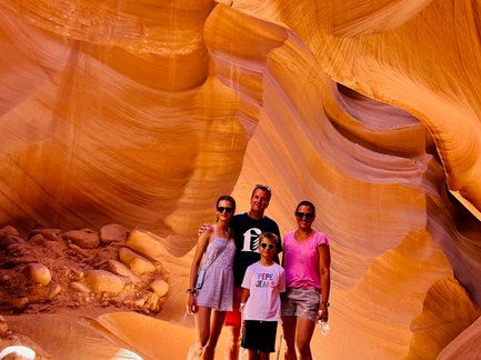 Eine Familie steht in der beeindruckenden Antelope Canyon, umgeben von orangefarbenen Sandsteinformationen und weichem Licht.
