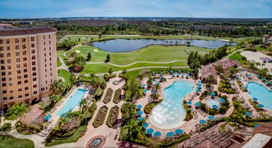 Ein luxuriöses Resort mit mehreren Pools, umgeben von üppigen Gärten und einem Golfplatz im Hintergrund.