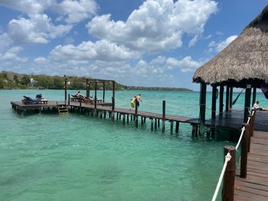 Kinder haben Spaß beim Sprung ins Wasser von einer Holzbrücke in der Lagune von Bacalar – Mexiko Reise mit Kindern