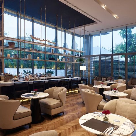 Elegante Lounge mit großen Fenstern, die einen Blick auf die grüne Umgebung bieten, und stilvollen Sitzbereichen für Gäste.