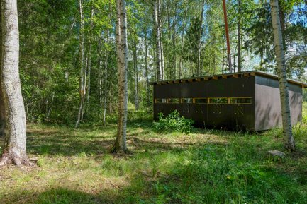 Ein modernes Beobachtungsgebäude steht inmitten eines dichten Waldes, umgeben von hohen Bäumen und üppigem Grün.