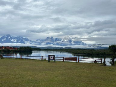 Ein ruhiger See spiegelt die majestätischen Berge wider, während Wolken sanft über die Gipfel ziehen.