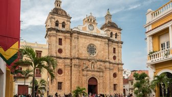 Die beeindruckende Kirche mit einer großen Uhr und roten Fenstern steht im Zentrum von Cartagena, umgeben von Menschen und Pflanzen.