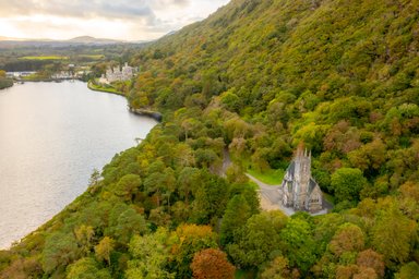 Eine beeindruckende Ansicht von Kylemore Abbey, umgeben von üppigem Grün und einem ruhigen See im Hintergrund.