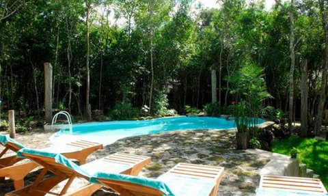 Ein einladender Pool umgeben von üppigem Grün, mit Liegen aus Holz und blauen Handtüchern für entspannende Stunden.