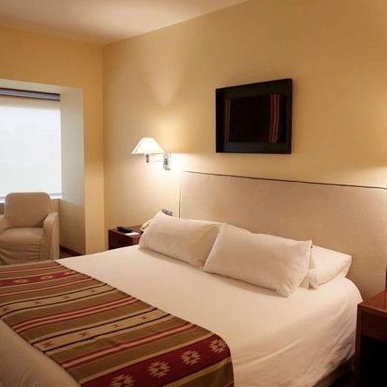 Ein gemütliches Hotelzimmer mit einem großen Bett, dekoriert mit bunten Kissen und einem stilvollen Überwurf.