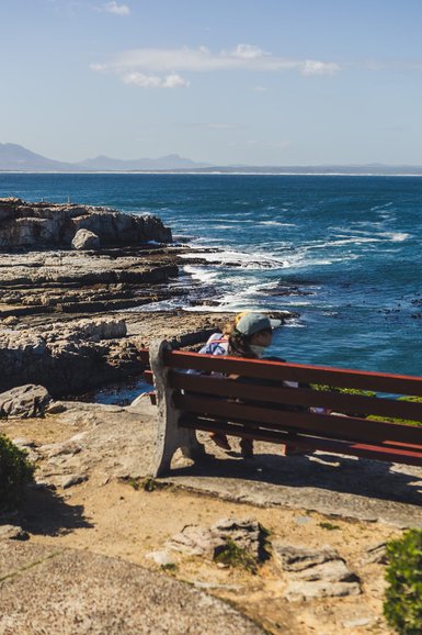 Kindern genießen die Aussicht auf einer Bank in Hermanus – Südafrika Familienreise