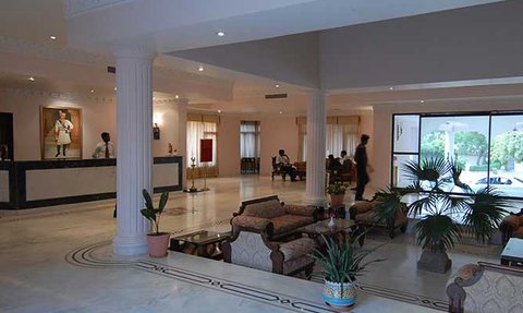 Der elegante Empfangsbereich des Heritage Resorts in Bikaner zeigt stilvolle Möbel und große Fenster mit Blick auf die Außenanlage.