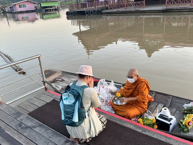 Touristin spricht mit Mönch, der in einem Boot sitzt in Uthai Thani- Thailand Familienreise