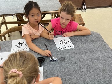 Kinder üben chinesische Kalligrafie auf Papier – China Reise mit Kindern