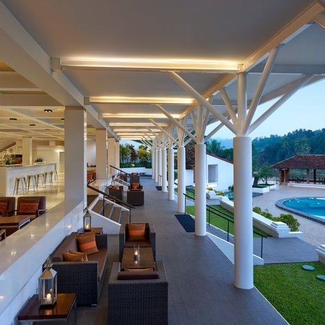 Ein eleganter Lounge-Bereich mit modernen Möbeln, der einen Blick auf einen Pool und eine grüne Landschaft bietet.