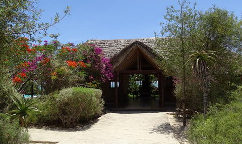 Ein einladender Eingang zu einem tropischen Hotel, umgeben von bunten Blumen und üppigem Grün.
