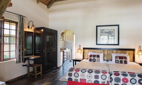 Ein gemütliches Schlafzimmer mit zwei Betten, bunten Kissen und einem rustikalen Holzdecke, das einladend wirkt.