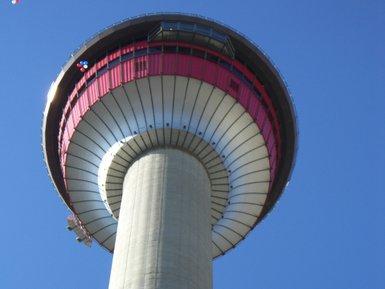 Der Calgary Tower ragt majestätisch in den blauen Himmel, mit einer markanten rot-weißen Aussichtsplattform oben.