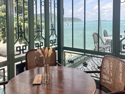 Ein eleganter Tisch mit einem Blumenarrangement steht in einem lichtdurchfluteten Raum mit Blick auf das Meer.