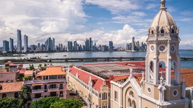 Die Skyline von Panama City erhebt sich majestätisch über das Wasser, umgeben von Wolken und strahlendem Himmel.